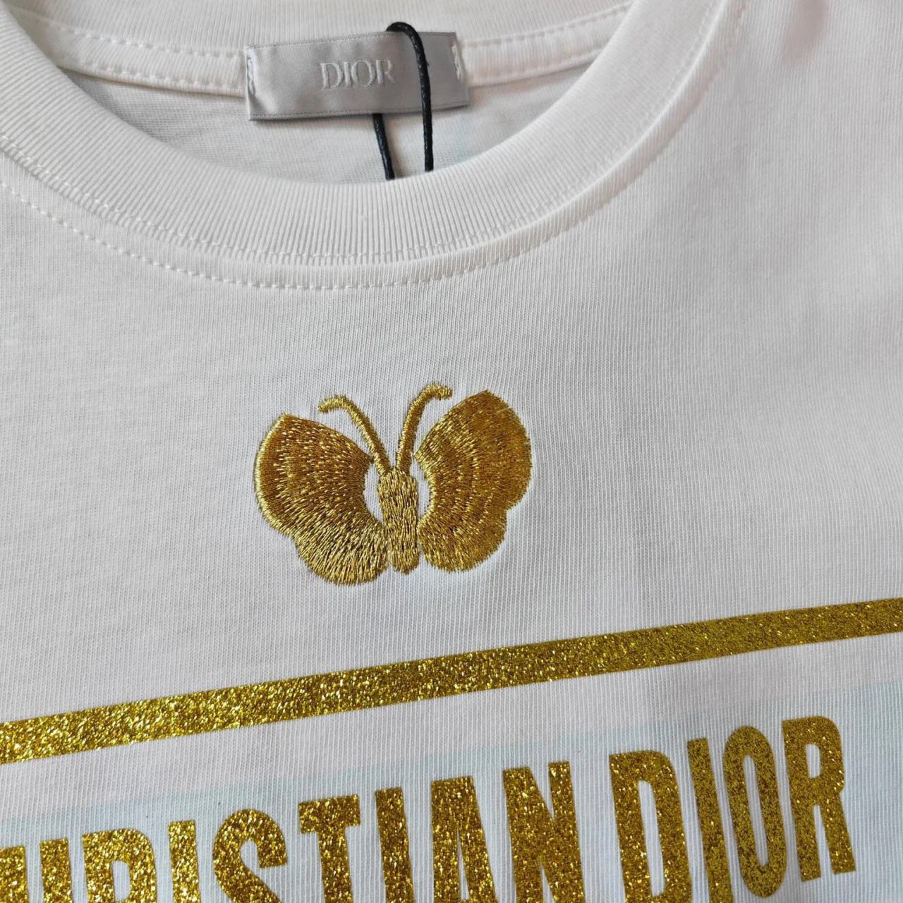 Camiseta con mariposa bordada y logo en tono dorado